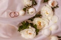 Flowers white wild rose and Golden wedding rings on white pearl color fabric