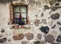 Flowers on the window of ancient building stone wall. Royalty Free Stock Photo