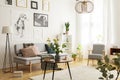 Flowers on wooden table next to grey couch in living room interior with lamp and posters. Real photo Royalty Free Stock Photo
