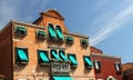 Flowery balcony in Venetian style with Windows and green awnings