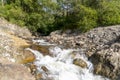 Creek beside rocks in wooded area with trees, water stream in nature Royalty Free Stock Photo