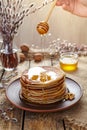 Flowing honey on stack of homemade traditional pancakes with nuts