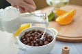 Flowing milk on cereal chocolate balls, chocolate flakes