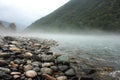 Flowing mountain stream with transparent water and stones. Fog is laying above the water. River valley in the mountains covered wi Royalty Free Stock Photo
