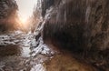 Flowing small creek running out icicle cave and washing big boulders. First sun rays lite young snow islands. Cold early winter Royalty Free Stock Photo