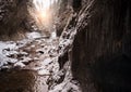 Flowing small creek running out icicle cave and washing big boulders. First sun rays lite young snow islands. Cold early winter Royalty Free Stock Photo