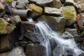 Flowing water from a pipe down to mossy rocks Royalty Free Stock Photo