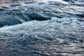 flowing water of a summer river with a small rapid waterfall at evening light Royalty Free Stock Photo