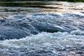 flowing water of a summer river with a small rapid waterfall at evening light Royalty Free Stock Photo