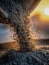 Flowing wet concrete pouring from chute with glowing sunlight in background creating dynamic construction scene at sunset Royalty Free Stock Photo