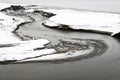 Flowing winding stream cutting a path to the sea through a winter beach Royalty Free Stock Photo