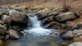 Flows over large rocks into a stream surrounded by more rocks and sparse Royalty Free Stock Photo