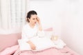 Flu. Closeup image of frustrated sick woman with red nose lying in bed in thick scarf