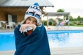 Flu, colds in the summer. Girl in a knitted hat with plaid with handkerchief sneezes, wipes her nose. Background nature, pool, gir Royalty Free Stock Photo