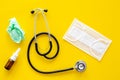Flu drops. Running nose concept. Wrinkled napkin near stethoscope and face mask on yellow background top view Royalty Free Stock Photo