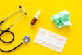 Flu drops. Running nose concept. Wrinkled napkin near stethoscope and face mask on yellow background top view Royalty Free Stock Photo