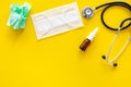 Flu drops. Running nose concept. Wrinkled napkin near stethoscope and face mask on yellow background top view copy space Royalty Free Stock Photo