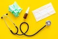 Flu drops. Running nose concept. Wrinkled napkin near stethoscope and face mask on yellow background top view Royalty Free Stock Photo