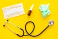 Flu drops. Running nose concept. Wrinkled napkin near stethoscope and face mask on yellow background top view Royalty Free Stock Photo