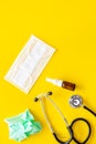 Flu drops. Running nose concept. Wrinkled napkin near stethoscope and face mask on yellow background top view copy space Royalty Free Stock Photo