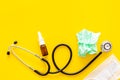 Flu drops. Running nose concept. Wrinkled napkin near stethoscope and face mask on yellow background top view copy space Royalty Free Stock Photo