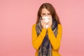 Flu season. Portrait of sick red hair girl wearing big scarf, sneezing and blowing nose, wiping with tissue, suffering temperature Royalty Free Stock Photo