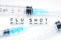 Flu shot text spelled with tiled letters standing next to a syringe