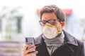 Flue and corona safety concept. Business man wearing face mask to protect himself and using smartphone. Outdoors