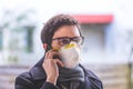 Flue and corona safety concept. Business man wearing face mask to protect himself and using smartphone. Outdoors