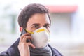 Flue and corona safety concept. Business man wearing face mask to protect himself and using smartphone. Outdoors