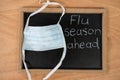 Flue season ahead written on chalk board with medical mask Royalty Free Stock Photo