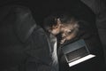 Fluffy cat lies at night in the bed near the laptop and looks at the screen Royalty Free Stock Photo