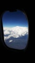 Fluffy clouds and snowy mountains  View from plane window Royalty Free Stock Photo