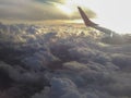 Fluffy clouds, sun and aircraft wing. Aerial view. Royalty Free Stock Photo