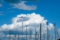 Fluffy cumulous clouds, deep blue sky and multiple masts