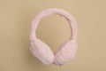 Fluffy earmuffs on beige background. Stylish winter accessory