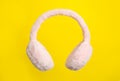 Fluffy earmuffs on yellow background. Stylish winter accessory