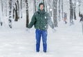 Fluffy flakes of snow fall on the girl. A young, happy girl is standing in the snow and enjoying the winter. The concept of winter