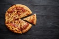 Fluffy pepperoni pizza in american style placed on rusty old black wooden table