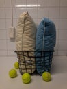 Fluffy pillows in a hamper with four tennis balls on a white surface Royalty Free Stock Photo