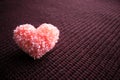 Fluffy pink thread heart on dark knitted burgundy background. Ha