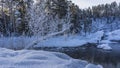 Fluffy snow lies on the banks of the blue unfrozen river