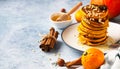 Fluffy spicy pumpkin pancakes with honey and nuts, fresh pumpkins and spices on blue stone background Royalty Free Stock Photo