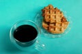 Fluffy waffles. They lie on a saucer. Next to a cup of coffee. Light green background. Shot close-up Royalty Free Stock Photo