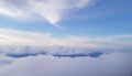 Fluffy white clouds blanket the horizon against a clear blue sky. Wispy, cirrus
