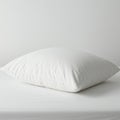 A fluffy white pillow rests on a white bed with a simple, smooth surface. The Royalty Free Stock Photo