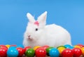 Fluffy white rabbit with pink bow guarding colorful eggs