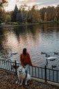 Fluffy white Samoyed dog in an autumn park with lake with swans and ducks