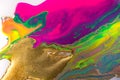 Fluorescent colorful liquid inks background with gold glitter particles. Marble imitation.