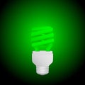 Fluorescent green economical light bulb glowing on a dark background. Save energy lamp. Royalty Free Stock Photo